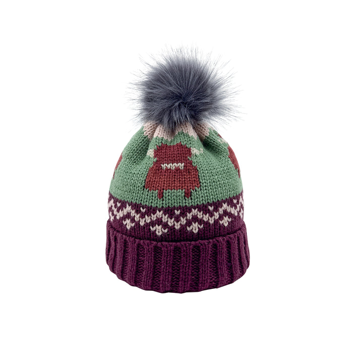 A knit winter beanie hat featuring a sage green upper section with a brown highland cow, a white and brown Fair Isle style band, and a ribbed dark purple cuff, topped with a large grey faux fur pom-pom.