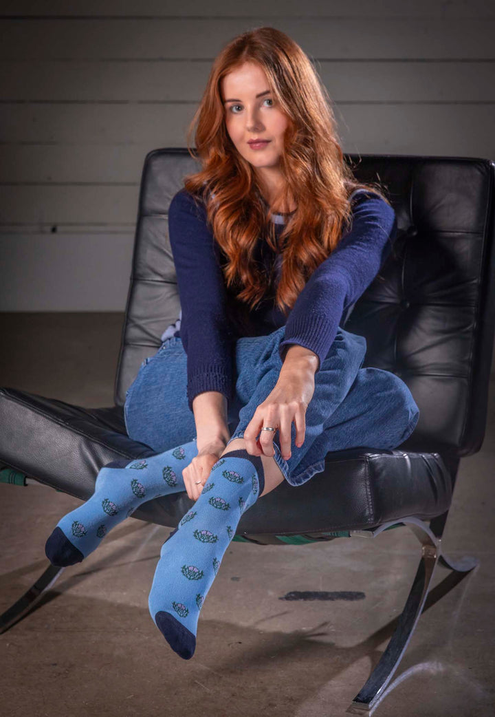 Woman sitting on a black chair wearing blue socks with a pattern.