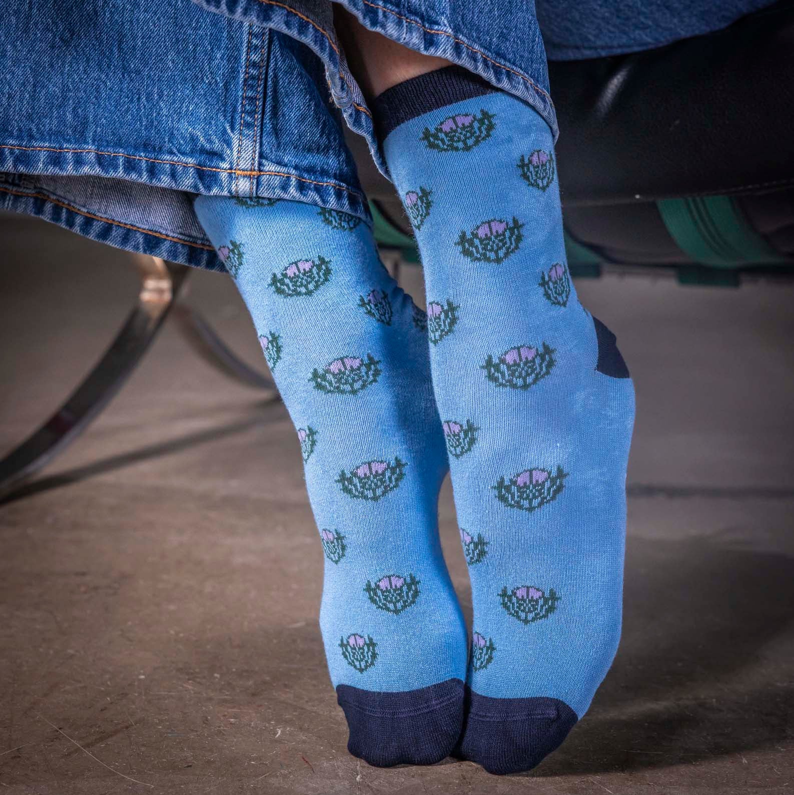Blue socks with floral pattern worn by a person sitting on a chair.