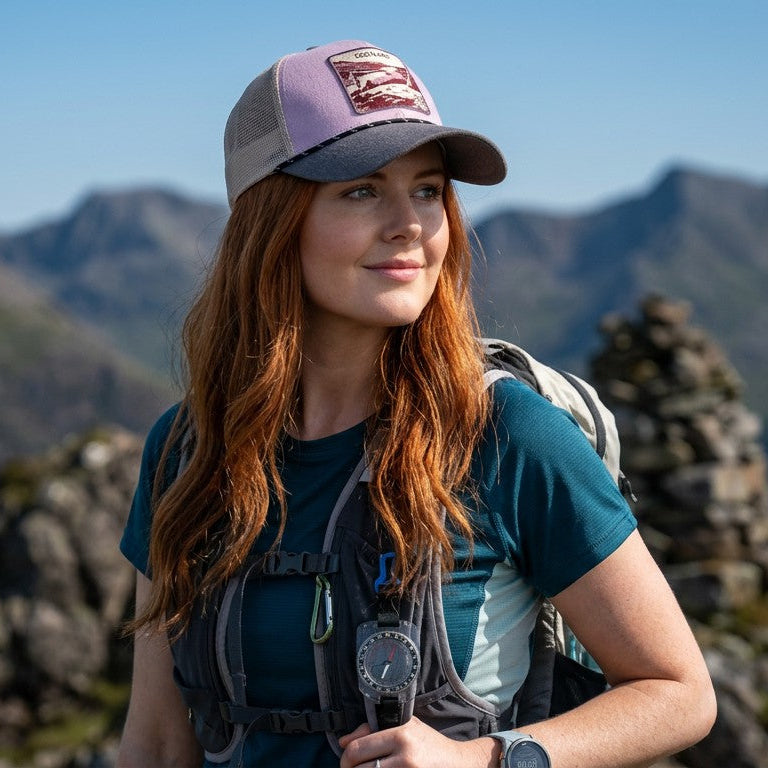 Female wearing a grey and pink trucker cap with an embroidered Scotland patch at the front.